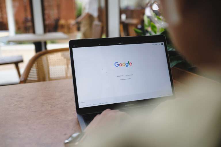 Startseite Person sitzt vor einem Laptop mit geöffneter Google-Startseite in einem Café