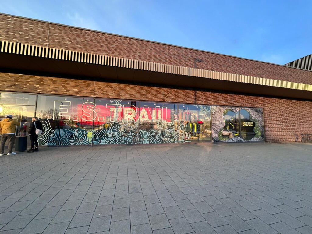 Großflächige Schaufensterfolierung mit Schriftzug „E.S. TRAIL“, Konturlinien und Naturmotiv über mehrere Glasfelder