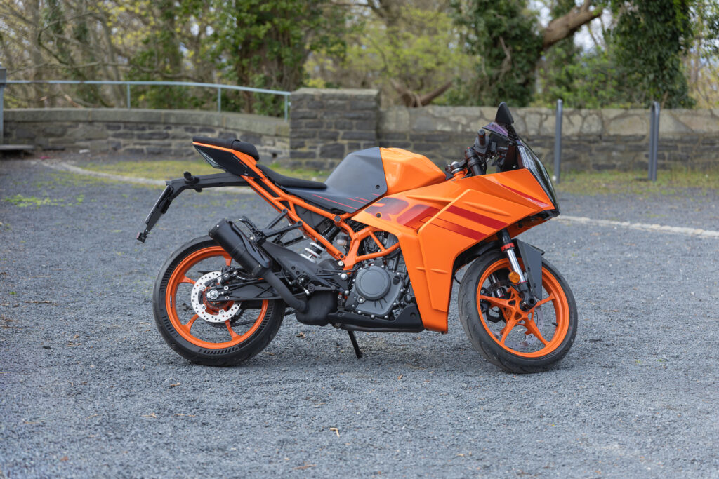 Motorad folieren lassen: Ein orangenes Motorrad steht auf der Straße. Es ist individuell mit einem Logo foliert.