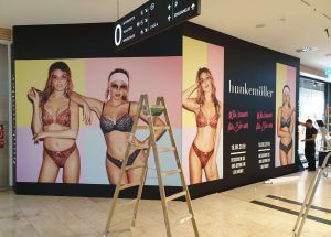 Hunkemöller_Schaufensterfolierung2 temporäre schaufensterfolierung als sichtschutz während der baustelle, gestaltet mit bunter motivfolie und models in hunkemöller-mode